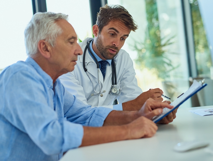 older man and doctor looking and pointing at a tablet
